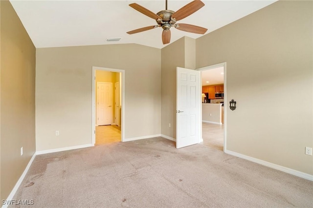 unfurnished bedroom featuring baseboards, visible vents, ceiling fan, vaulted ceiling, and light carpet