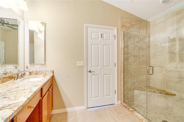 full bathroom featuring tile patterned floors, a stall shower, baseboards, vanity, and vaulted ceiling