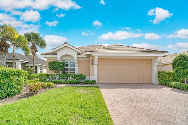 ranch-style house with an attached garage, stucco siding, a front lawn, a tile roof, and decorative driveway