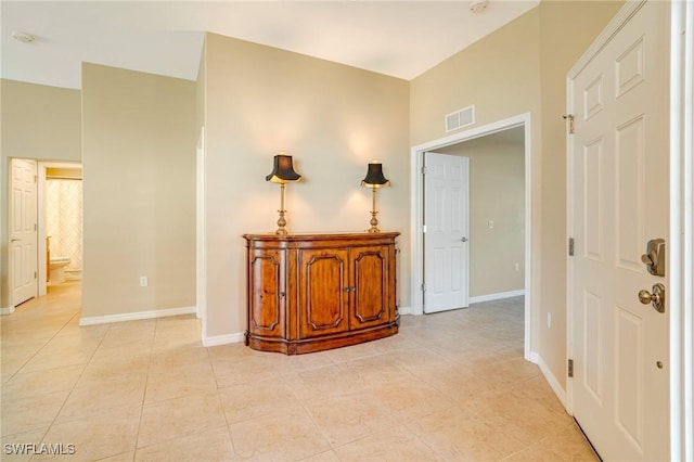 corridor with light tile patterned flooring, visible vents, and baseboards