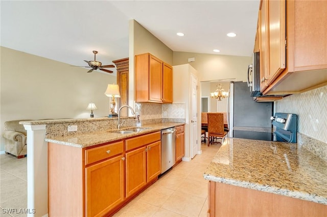 kitchen featuring light stone countertops, a peninsula, a sink, decorative backsplash, and appliances with stainless steel finishes