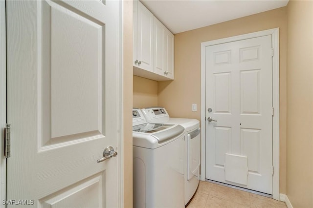 washroom with washing machine and dryer, light tile patterned floors, and cabinet space