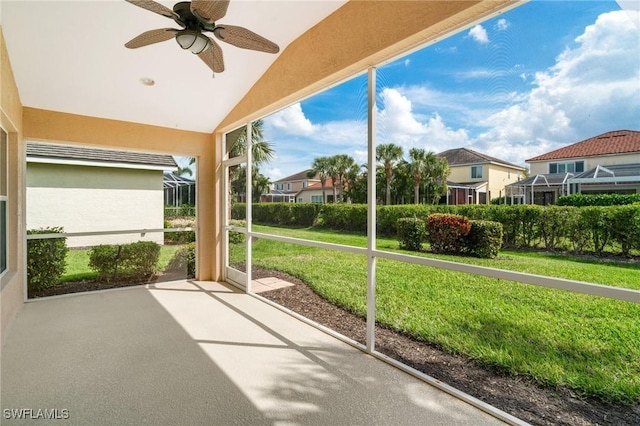 unfurnished sunroom featuring a residential view, a ceiling fan, and lofted ceiling