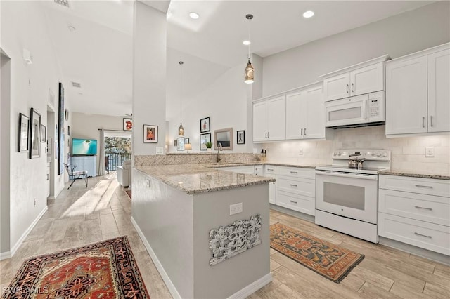 kitchen with backsplash, a peninsula, white appliances, white cabinetry, and a sink