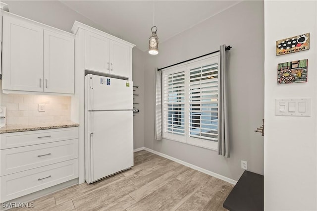 kitchen with white cabinets, light wood-style flooring, tasteful backsplash, and freestanding refrigerator