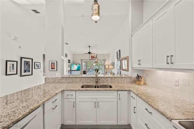 kitchen featuring light stone countertops, visible vents, a sink, decorative backsplash, and white cabinets