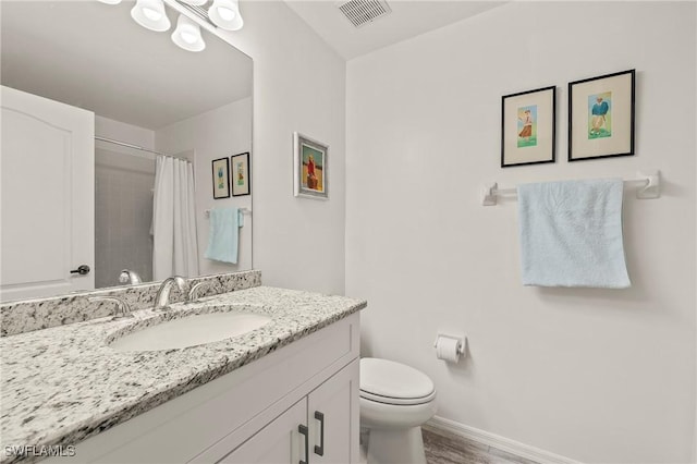 full bath with vanity, wood finished floors, baseboards, visible vents, and toilet