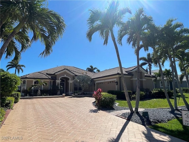 view of front of property with stucco siding, an attached garage, decorative driveway, and a front yard