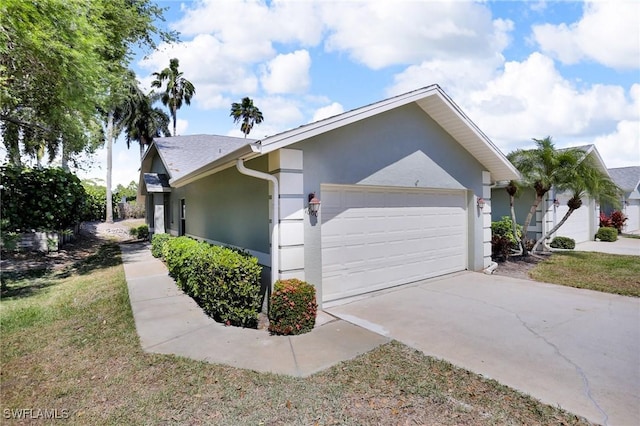 view of side of property with stucco siding, concrete driveway, and a garage