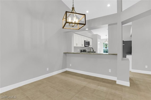 kitchen featuring baseboards, a chandelier, pendant lighting, appliances with stainless steel finishes, and white cabinets