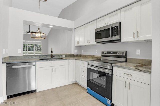 kitchen featuring a sink, light stone counters, appliances with stainless steel finishes, white cabinets, and vaulted ceiling