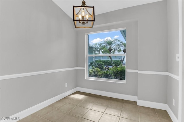 tiled empty room with baseboards and a chandelier