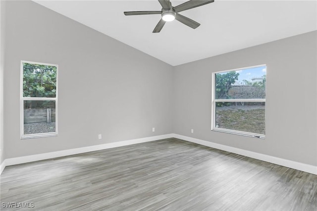 empty room with vaulted ceiling, wood finished floors, baseboards, and ceiling fan