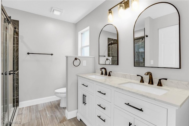 bathroom with an enclosed shower, double vanity, toilet, and a sink