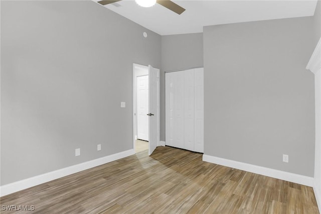 spare room with wood finished floors, a ceiling fan, baseboards, and vaulted ceiling