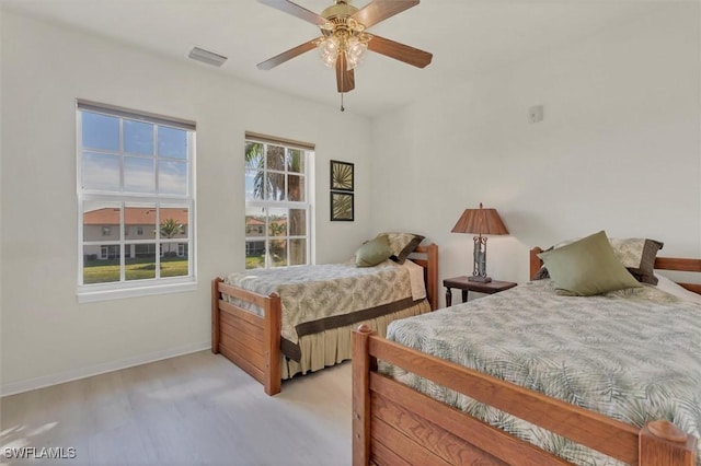 bedroom with visible vents, baseboards, wood finished floors, and a ceiling fan