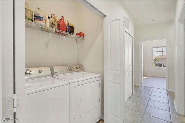 laundry area with washer and dryer, laundry area, light tile patterned floors, and baseboards