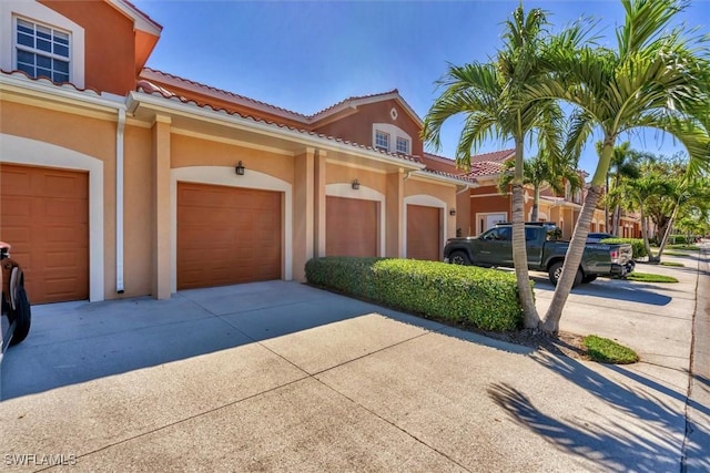 exterior space featuring stucco siding, concrete driveway, and a tile roof