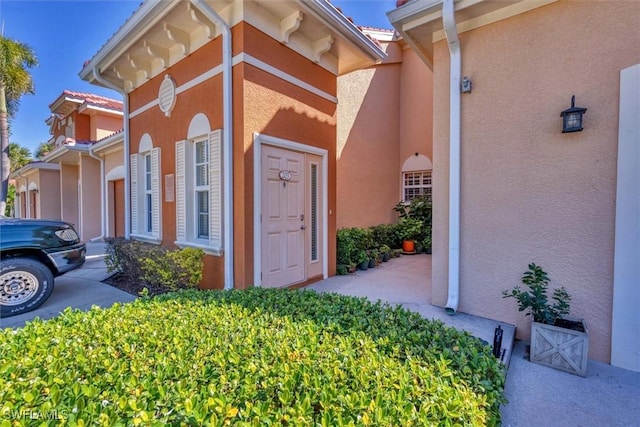 doorway to property with stucco siding and a tiled roof