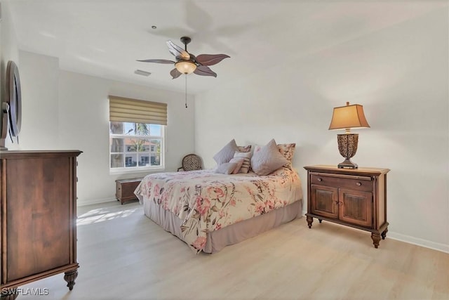 bedroom featuring visible vents, baseboards, light wood-style floors, and a ceiling fan