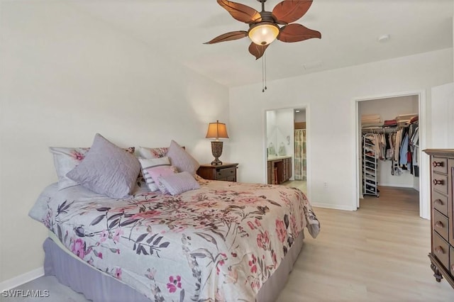 bedroom featuring baseboards, ceiling fan, light wood-style floors, a closet, and a walk in closet