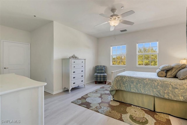 bedroom with a ceiling fan, light wood-style floors, visible vents, and baseboards