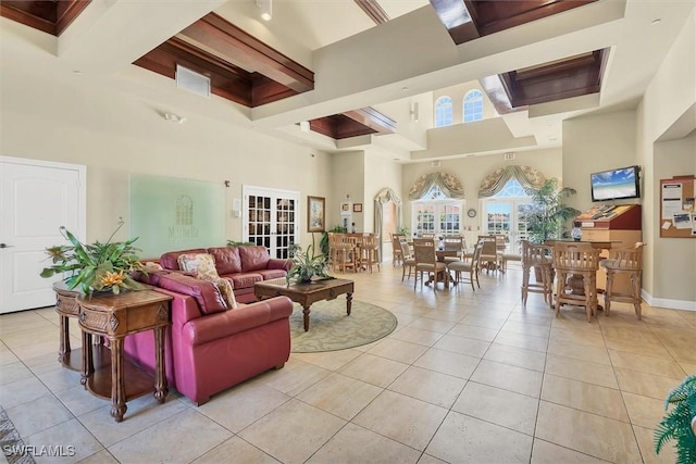 living area featuring light tile patterned flooring, baseboards, and a towering ceiling