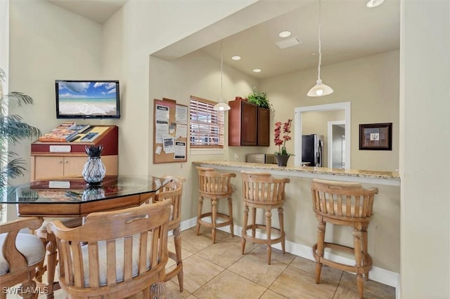 kitchen featuring decorative light fixtures, light tile patterned flooring, baseboards, and freestanding refrigerator