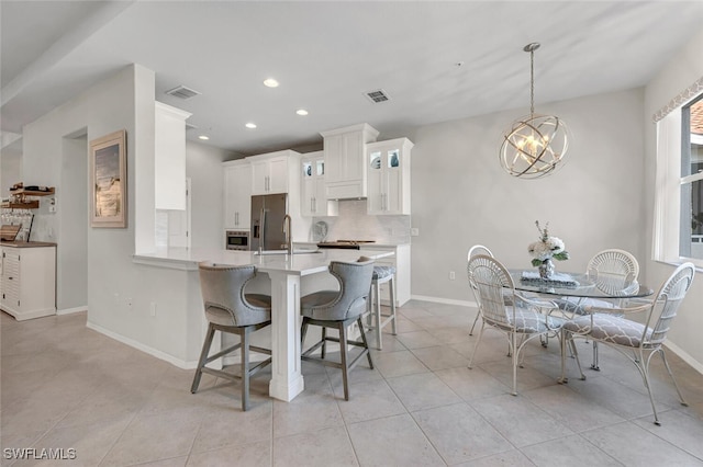 kitchen with visible vents, a breakfast bar, decorative backsplash, and white cabinetry