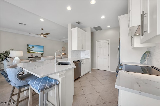 kitchen with visible vents, a peninsula, stainless steel dishwasher, white cabinetry, and a sink