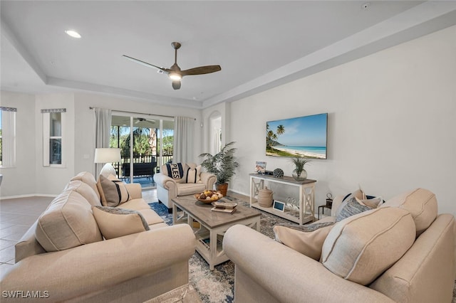 living room featuring tile patterned floors, a raised ceiling, recessed lighting, baseboards, and ceiling fan