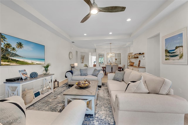 living room featuring recessed lighting, a tray ceiling, and ceiling fan with notable chandelier