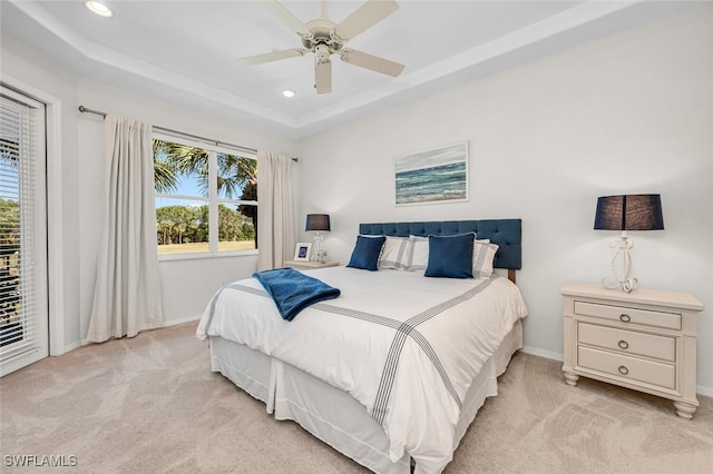 bedroom with a raised ceiling, multiple windows, recessed lighting, and light carpet