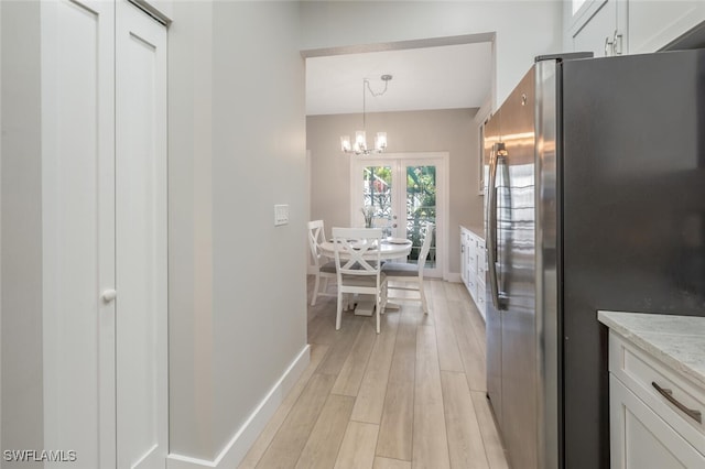 kitchen with baseboards, light wood finished floors, a chandelier, and freestanding refrigerator
