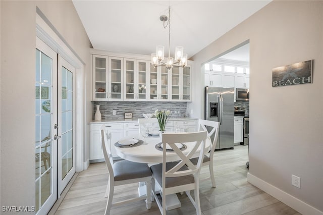 886 Tanbark Dr SW Unit 103, Naples, FL 34108 - dining room featuring a chandelier, baseboards, and light wood-type flooring