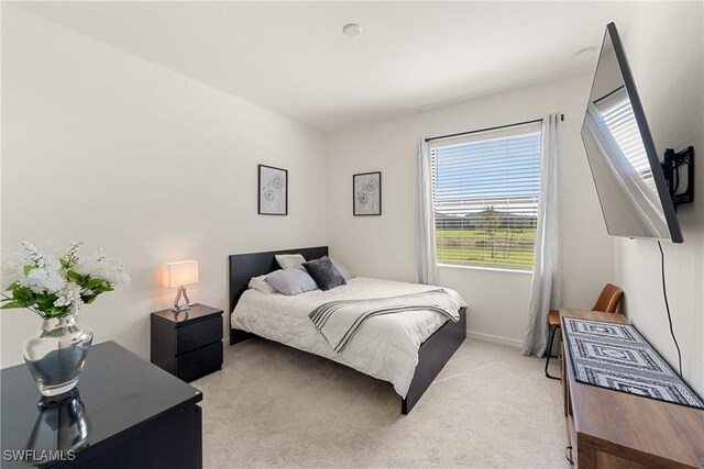 bedroom with light carpet and baseboards