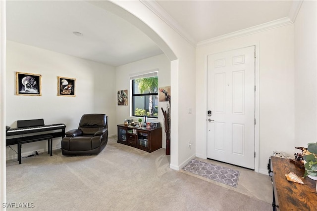 entryway with ornamental molding, arched walkways, light colored carpet, and baseboards