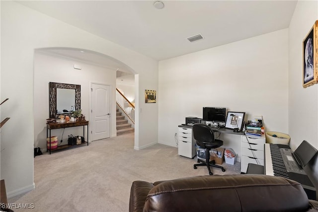 office space with baseboards, visible vents, arched walkways, and light colored carpet