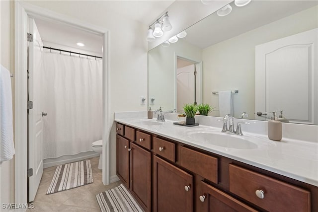 bathroom with double vanity, a sink, toilet, and tile patterned floors