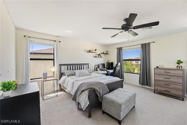 bedroom with light carpet, ceiling fan, visible vents, and baseboards