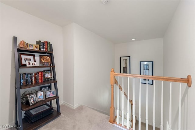 hallway with carpet flooring, an upstairs landing, and baseboards