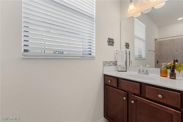 bathroom featuring tiled shower, vanity, and a wealth of natural light