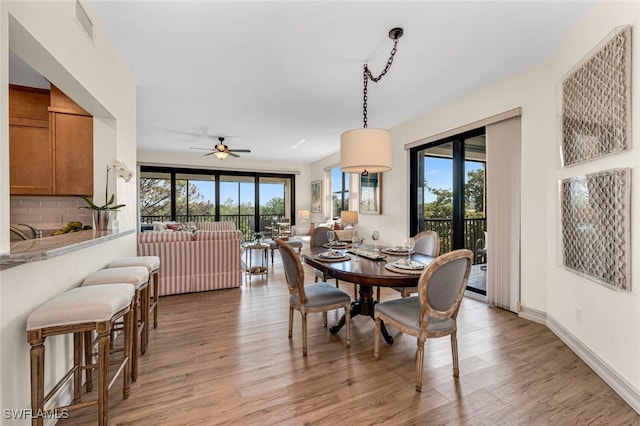 dining room featuring visible vents, baseboards, light wood finished floors, and ceiling fan