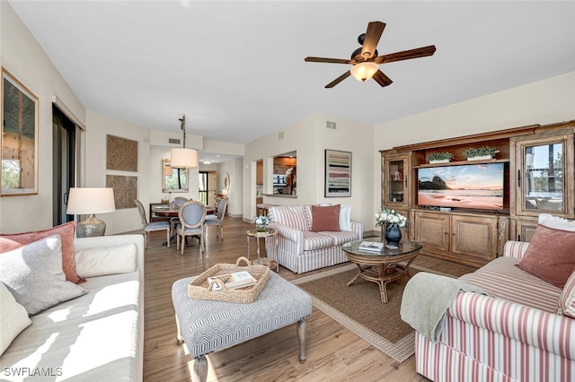 living area featuring visible vents, light wood finished floors, and ceiling fan