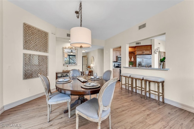 dining area featuring visible vents, light wood-style flooring, and baseboards