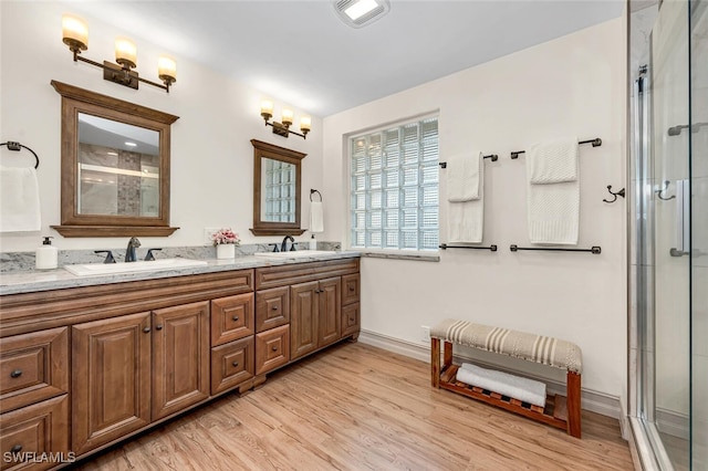 full bath featuring an enclosed shower, visible vents, wood finished floors, and a sink