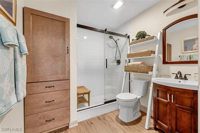 full bath with a stall shower, toilet, vanity, and wood finished floors