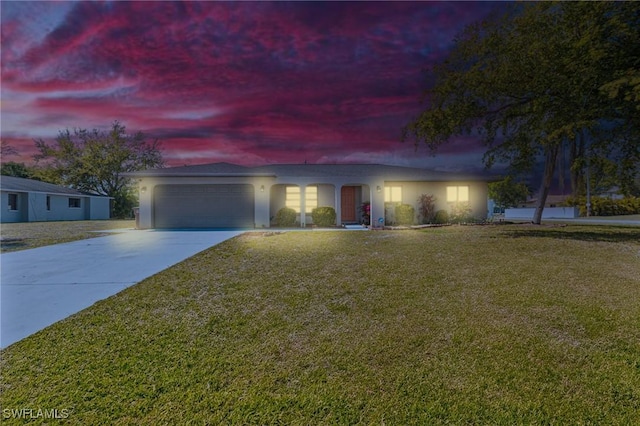 ranch-style home with a garage, a yard, driveway, and stucco siding