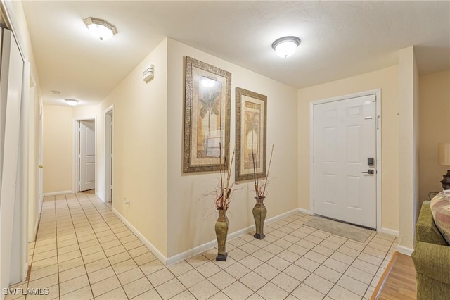 entryway with light tile patterned flooring and baseboards