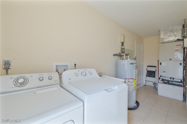 laundry area with heating unit, washing machine and dryer, electric water heater, light tile patterned flooring, and laundry area